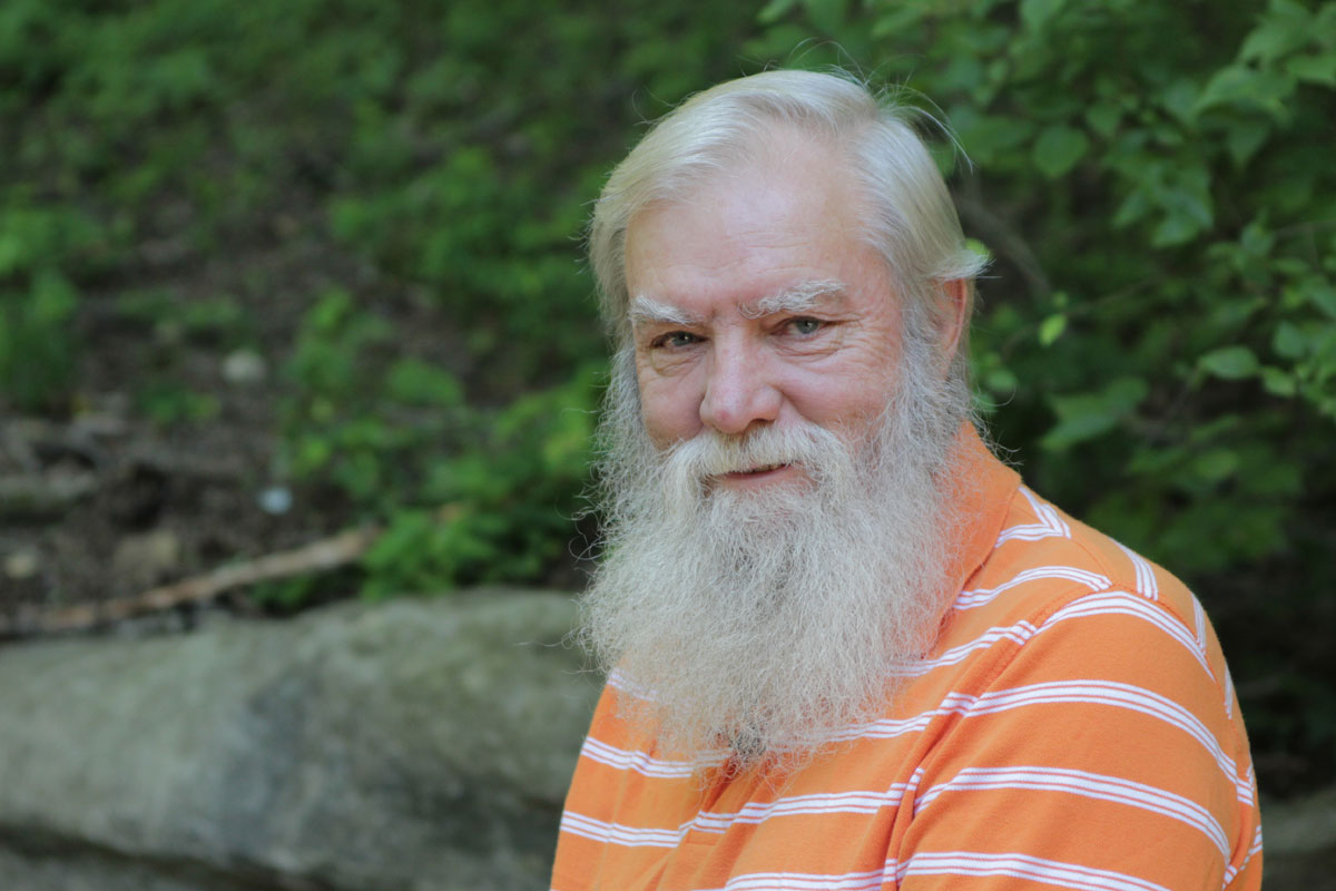 Older man with white beard wearing orange polo shirt