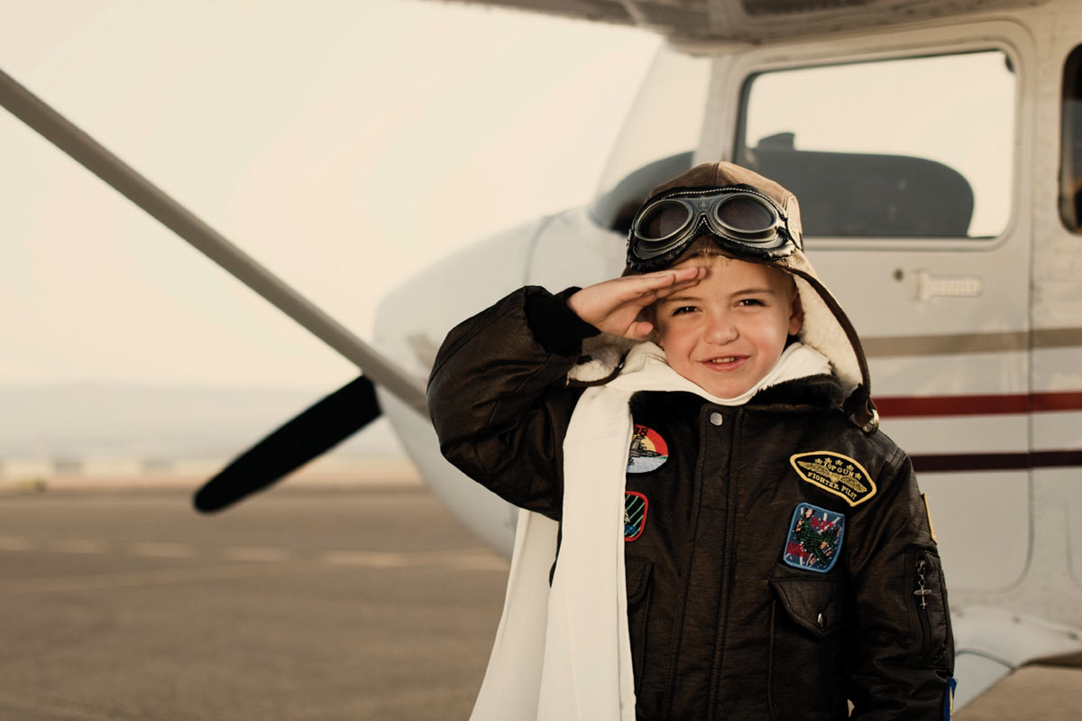 Miniature pilot stands beside plane and salutes