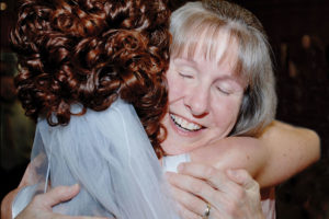 A bride with curly red hair hugs her mother