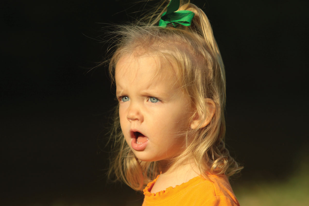 Angry little blonde-haired girl wearing orange and green